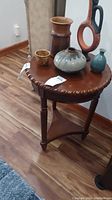 Round dark wood plant stand or side table with ceramic and pottery pieces on top