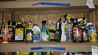Full shelf view showing multiple pest and yard control products including sprays and liquid containers with various label designs and brands, some with spray nozzles.
