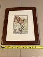 Front view of framed art print featuring a wolf and its artistic reflection, with measurement tape showing frame width approximately 14 inches.