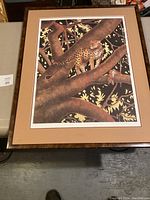 Overall framed print showing leopard standing on thick branches of a tree with detailed foliage.