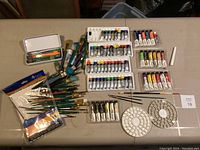 Overview of the entire lot on table including paint brushes, paint tubes, palettes, and tools