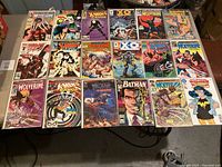 Top view of 19 comic books on a table showing characters like Wolverine, Wonder Woman, X-Men Havok, Batman, and X-O Manowar.