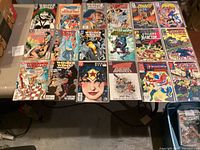 Photo showing full lot of 19 comic books spread on table, mainly Wonder Woman with some other titles