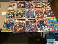 Top view of 15 comic books arranged in three rows, showing titles and colorful illustrated covers mostly from Marvel and Malibu Comics.