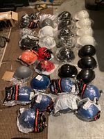 Multiple new hard hats in various colors and styles laid out on floor, some in packaging