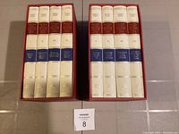Two red slipcases holding eight hardcover volumes of Edward Gibbon's History of the Decline and Fall of the Roman Empire, all volumes visible with titles on spines.