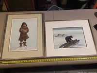 Two framed prints side by side on table