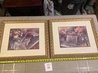 Two framed limited edition art prints with musical instruments and flowers, placed side-by-side with measuring tape showing approximately 23 inches width each.