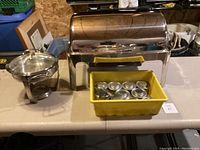 Photo showing stainless steel chafing dish, warming tray, and yellow bin with small containers.