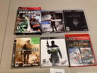 Photo showing six PlayStation 3 game cases: Uncharted double pack, Tomb Raider, Skyrim, Call of Duty Modern Warfare, Call of Duty Modern Warfare 3, God of War Collection.