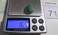 Faceted green jade gemstone on a digital scale showing a weight of 16.5 carats.