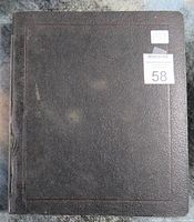 Closed black textured binder with wear marks and a lot number sticker on the front.