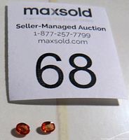Photo showing two orange topaz gemstones with auction label number 68 in background.