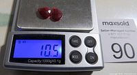Two pear-shaped faceted rubies placed on a digital scale showing total weight of 10.5 carats.