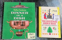 Two vintage cookbooks placed side by side showing front covers and publication years: Betty Crocker's Dinner in a Dish (1965) with green cover, and The Christmas Cookie Book (1949) with a yellow and white illustrated cover.