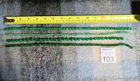 Four emerald-colored bead necklaces laid out with measuring tape showing lengths approx. 16-18 inches.