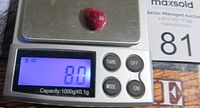 Ruby stone on digital scale displaying weight as 8.0 carats, showing verification of weight and authenticity.