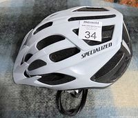 Side view of white Specialized bike helmet showing brand logo and ventilation slots.