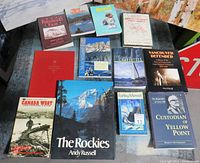 Vintage Canadiana books laid out on a surface showing titles including The Rockies by Andy Russell, Canada West, Farley Mowat's The Black Joke, Vancouver Defended, and other titles concerning BC and Canada history and nature.