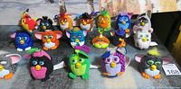 Full view of 21 vintage Furby toys in various colors and styles arranged on wrestling mat background