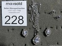 Full set photo showing necklace with chain and matching earrings on a display pad with seller auction tag.