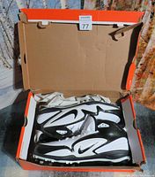 Nike black and white cleat shoes inside open Nike orange shoebox