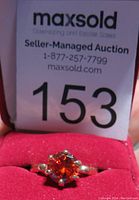 Front view of the red gemstone ring with the auction number tag visible.