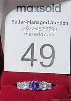 Front view of the ring showing the central amethyst and surrounding cubic zirconia stones on a red velvet display case.