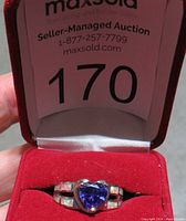 Front view of the ring in red display box with auction number visible.