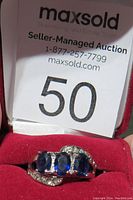 Ring displayed in red jewelry box with lot number card