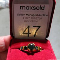 Gold tone ring with smoky quartz stones displayed in red box with auction lot card visible