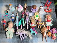 Full view of various vintage dolls spread on blanket including Barbie, My Little Pony, baby dolls, and other fashion dolls.