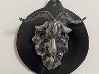 Front view of the detailed goat head with large curved horns on a black backing