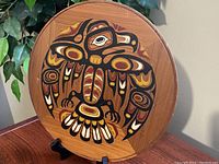 Front view of circular wooden plaque showing detailed Indigenous eagle artwork in earthy colors.