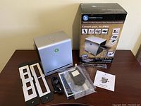 Converter device, original box, film holders, USB cable, power adapter, and manual placed on a table.