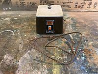 Full front view of the Glastar stained glass grinder with power switch and power cord visible, placed on a worn workbench.