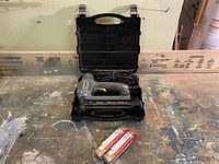 Stanley electric brad nailer in open black carrying case, two packs of nails in front.