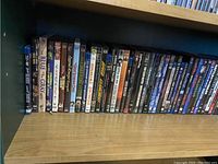 First shelf showing assorted DVD and Blu-ray movies including titles: The Blues Brothers, Little Women, The Phantom of the Opera, The Social Network