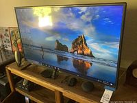 Front and side view of the LG 42 inch TV showing screen image and stand on a wooden shelf.