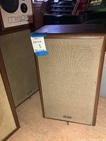 Front view of one speaker showing wood veneer cabinet, cloth grille and Advent logo