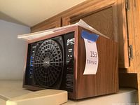 View of the front side of the Eco Quest Breeze AT air purifier, showing a wood grain finish and central fan with multiple control LEDs on the left.