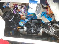 Overview photo showing three vintage cameras including Canon A-1, Canon AE-1, and Yashica Lynx 5000 with various film boxes and accessories in the lot.