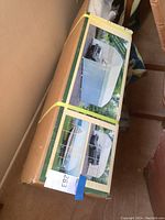 Factory-sealed cardboard box showing color photos of installed carport cover over vehicle.