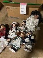 Lot of seven dolls dressed in international costumes laid on carpet with cardboard box background