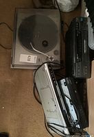 Technics turntable with dust cover and detached dome, JVC VCR with remote, Magnavox and Sylvania DVD players stacked.