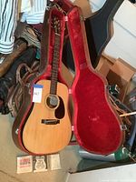 Lyle guitar inside open hard shell case with string packs and picks visible