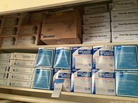 Shelving with multiple boxes of sterile non-woven gauze sponges, post-op sponges, and medical supplies.