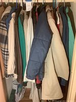 Full view of men's large coats and jackets hanging on rail, shows various colors, materials, and brands including corduroy and insulated jackets.