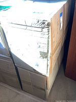 Two large cardboard boxes stacked, containing bubble mailer envelopes, taped and labeled