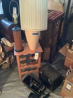 Overview of the lot showing the sewing machine, black case on floor, wooden wine rack, two lamps and small wooden side table.